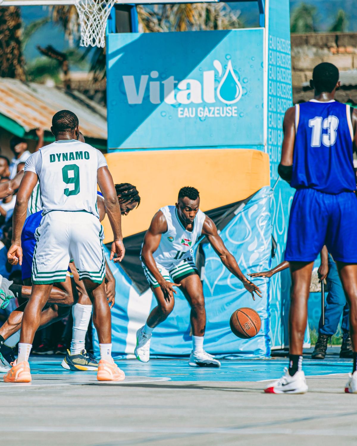 A basketball game on an outdoor court with a sponsor board
