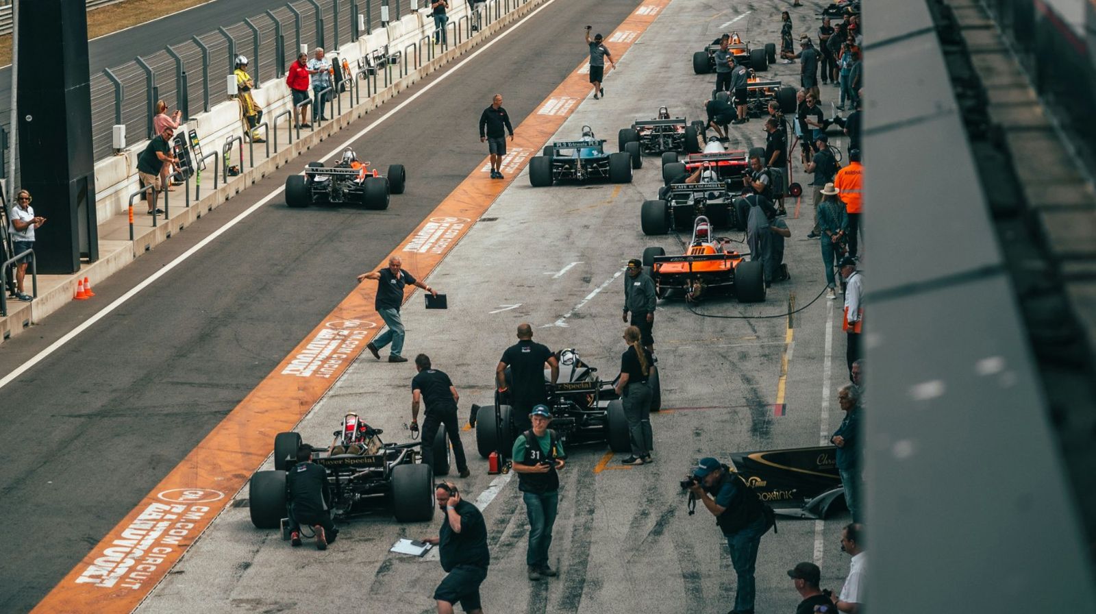 Racing cars and mechanics in the pit lane of a circuit